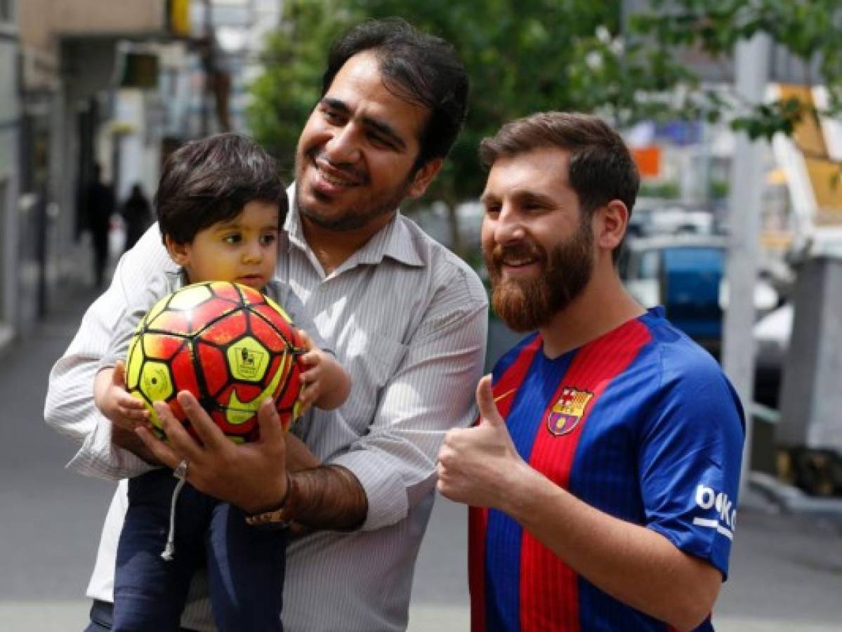 Reza Parastesh, a doppelganger of Barcelona and Argentina's footballer Lionel Messi, poses for a picture with fans in a street in Tehran on May 8, 2017. / AFP PHOTO / ATTA KENARE