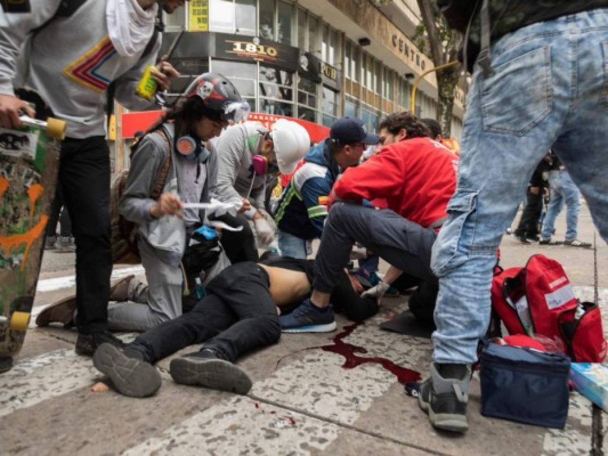 TOPSHOT - EDITORS NOTE: Graphic content / This image taken on November 23 ,2019 shows paramedics helping Dylan Cruz (18) after being hurt by a gas canister shot by a member city's anti-riot police (Esmad) during a protest in Bogota. - The young protester died November 25, 2019, after being injured by the public force on Saturday during protests against the government of Colombian President Ivan Duque. (Photo by Camila LASALLE RAMIREZ / AFP)