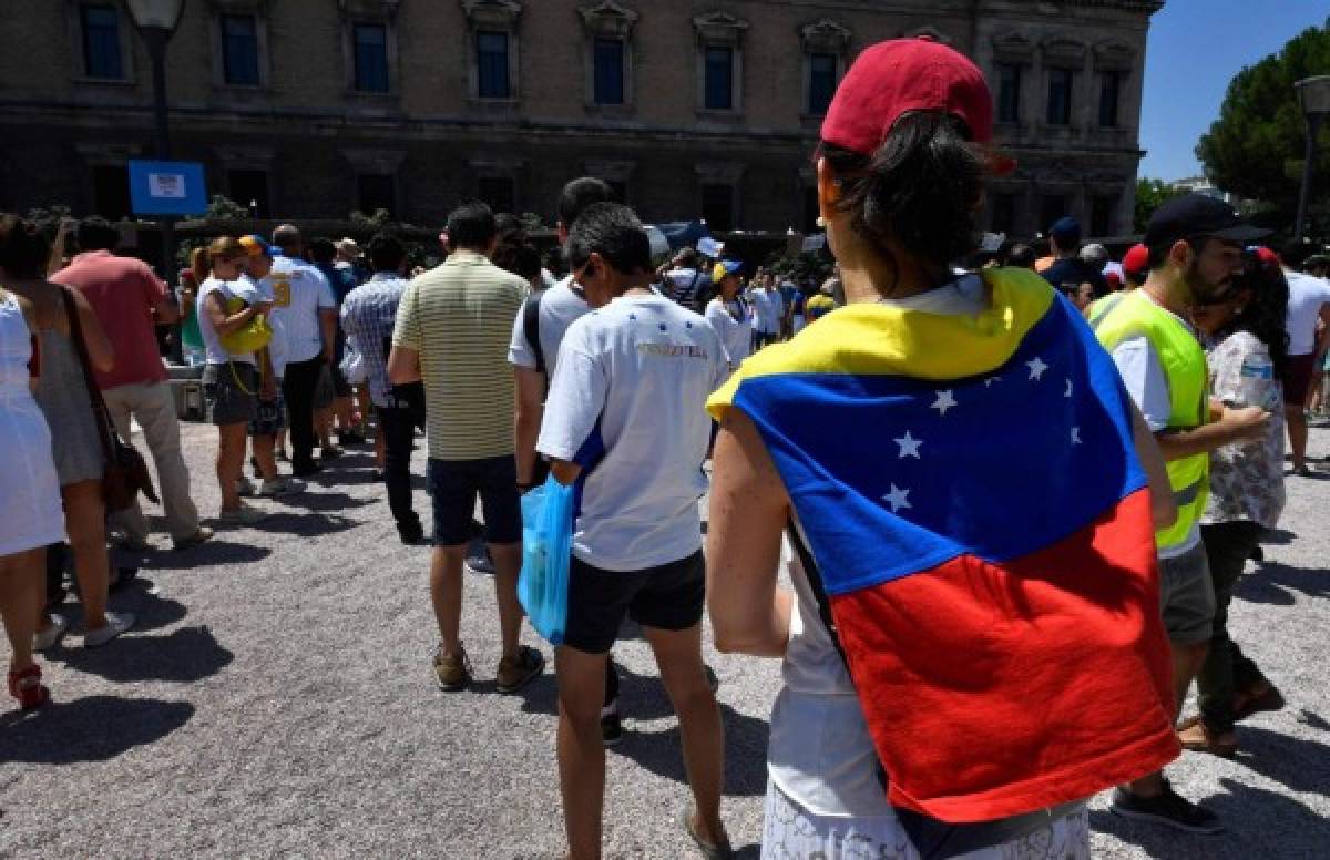 Venezuelan residents in Madrid queue to vote during a symbolic plebiscite on president Maduro's project of a future constituent assembly, called by the Venezuelan opposition and held at the Puerta del Sol in Madrid on July 16, 2017.Hundreds of Venezuelans queued in the blazing heat in Madrid today to vote in an opposition-organised vote to measure public support in Venezuela for President Nicolas Maduro's plan to rewrite the constitution. / AFP PHOTO / GERARD JULIEN