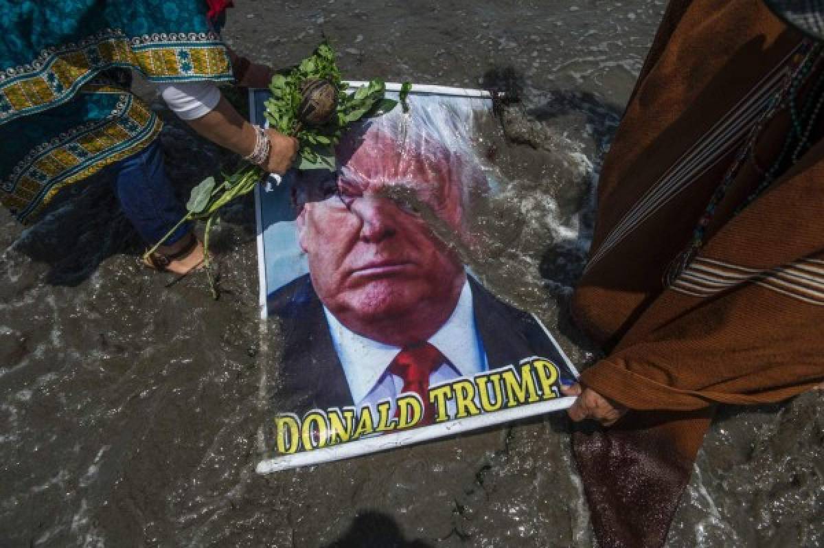 Los Chamanes sumergen en el agua la foto de Trump, lo llenan de arena y el chaman Mejía se lanza encima de él en una maniobra que se asemeja a un 'tackle' de rugby. Foto: AFP