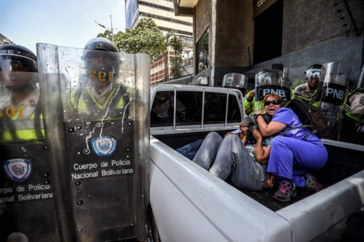 Mujeres se cubren por los enfrentamientos entre policías y protestantes. Foto: AFP