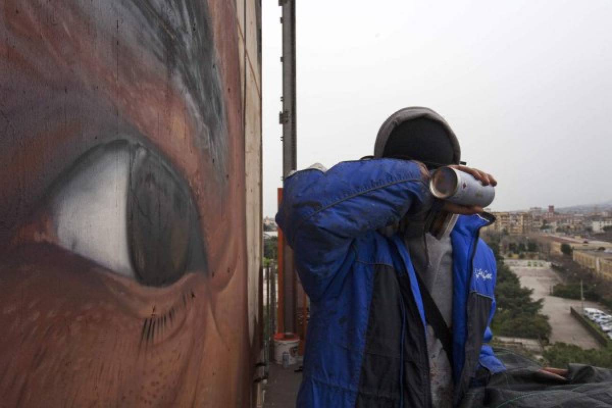 El artista Jorit Agoch, subido en un andamio, pinta el mural.