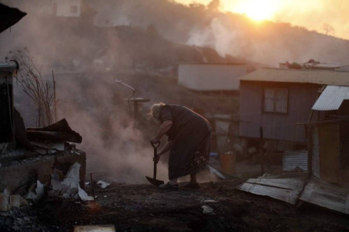 Nora Villarroel, de 59 años, trata de extinguir totalmente el fuego que devoró por completo su casa en Valparaíso, Chile, foto: AP.