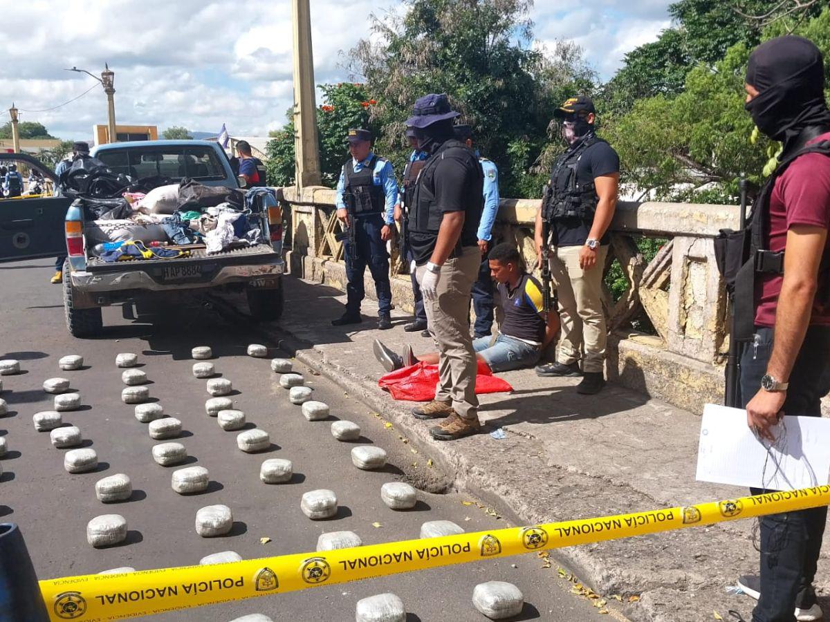 Agentes contabilizan la supuesta marihuana encontrada en el vehículo, mientras el conductor permanece detenido, sentado en un puente que conecta la ciudad.