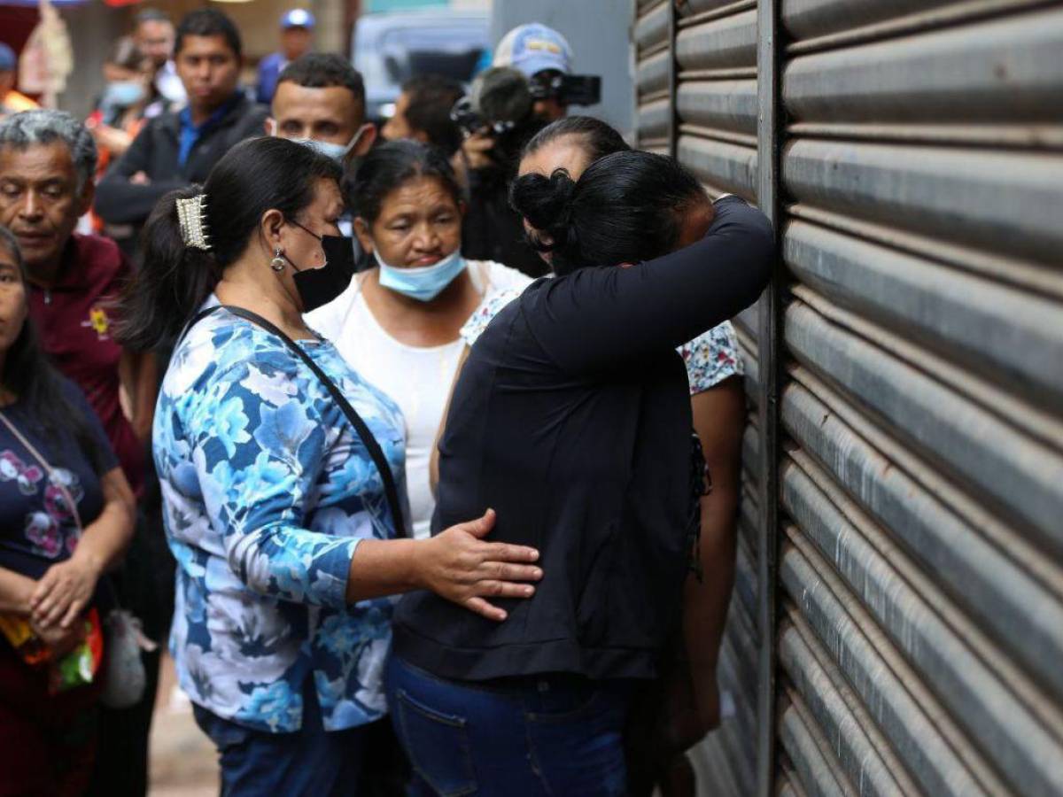 Familiares de Paola Henriquez y de Belinda Henriquez lloran sobre la cortina de acceso al área de entrega de cuerpos en la morgue del Ministerio Público.