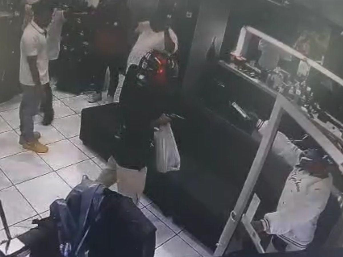 Momento en que uno de los delincuentes levantaba el arma en señal de amenaza, mientras el otro guardaba lo robado en una bolsa.