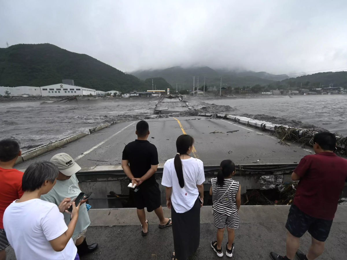 Varias personas observan un puente sobre el río Dashihe que se hundió arrastrado por las aguas tras las lluvias torrenciales en Pekín.