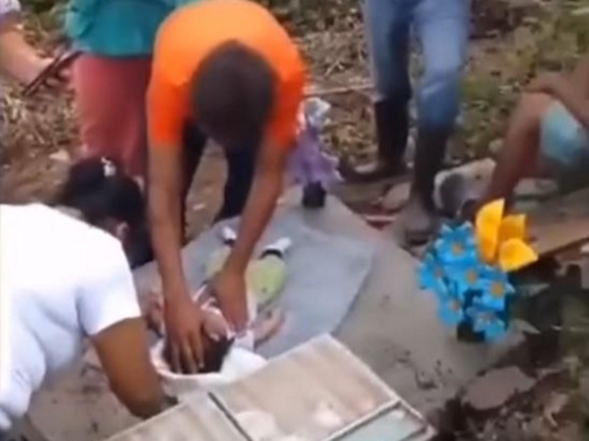 Momento en que el bebé fue rescatado de la tumba y que presentaba aún temperatura corporal y latidos, según la familia.