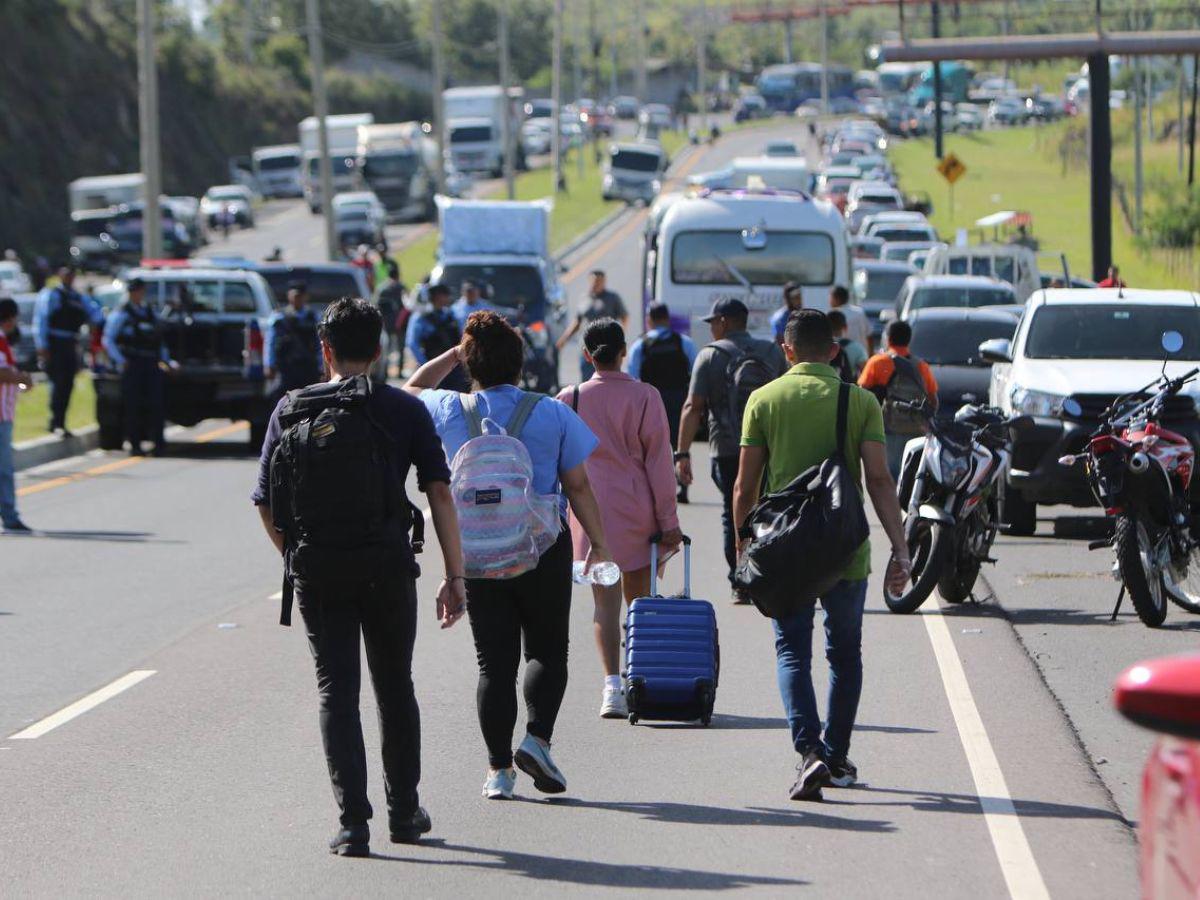 Con maleta en mano y niños en brazos, hondureños caminan por protesta en carretera CA-5