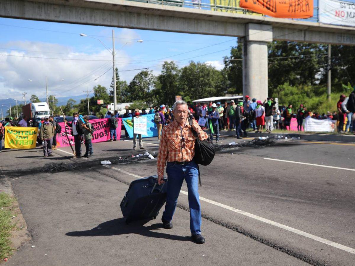 Con maleta en mano y niños en brazos, hondureños caminan por protesta en carretera CA-5