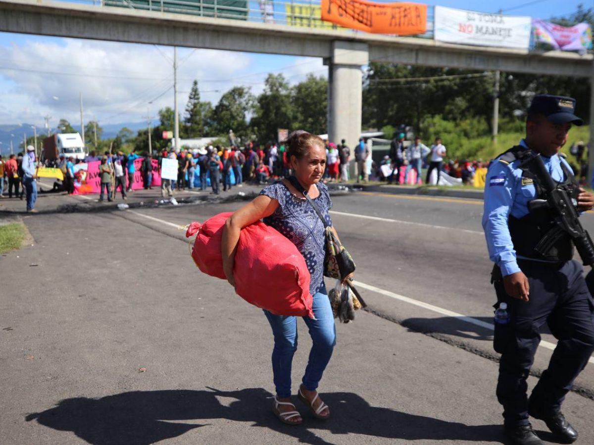 Con maleta en mano y niños en brazos, hondureños caminan por protesta en carretera CA-5