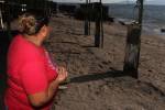 Una mujer mira el mar en la playa de Cedeño. Su casa está hecha de madera y lámina, pues ha perdido su patrimonio varias veces debido a la elevación del mar. Se resiste a irse de la zona.