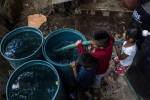 Niños ayudan a llenar barriles de agua del reparto semanal de agua en su barrio de la Ciudad de México.