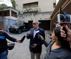 El abogado Joel García, que representa a Juan José Márquez, el tío encarcelado del líder opositor Juan Guaidó, habla con la prensa afuera del edificio de apartamento donde vive su cliente, y donde un vehículo de la policía militar permanece estacionado, en Caracas, Venezuela. (AP Foto/Ariana Cubillos)