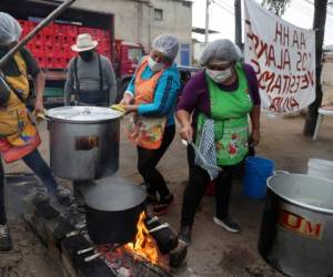 Eso sucede por ejemplo en el distrito Villa María del Triunfo, donde mujeres y hombres que perdieron sus empleos preparan los alimentos usando leña en varias ollas de 50 litros de capacidad. AP.