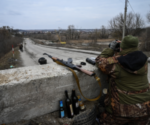 Un militar ucraniano mira a través de binoculares hacia la ciudad de Stoyanka en un puesto de control antes del último puente en la carretera que conecta Stoyanka con Kiev, el 6 de marzo de 2022.