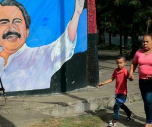 Una mujer y niños caminan junto a un mural que representa al presidente de Nicaragua, Daniel Ortega, en Managua el 10 de enero de 2022, día en que inicia su cuarto mandato.