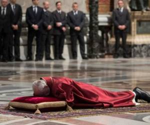 Postrado, con su mirada hacia el suelo y sus vestiduras rojas, el Papa Francisco introdujo la ceremonia de adoración a la cruz este Viernes Santo en la Basílica de San Pedro. Foto AFP