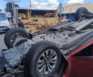 Un pick-up rojo quedó volcado luego de que una rastra, que transportaba tarimas de madera, lo embistiera violentamente.