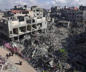 La gente pasa junto a edificios destruidos tras el bombardeo israelí de Gaza, en Bureij, en el centro de la Franja de Gaza, el 14 de noviembre de 2023.