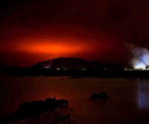 El brillo rojo del magma que fluye desde el volcán Fagradalsfjall en erupción detrás de la emblemática Laguna Azul, a unos 45 km al oeste de la capital de Islandia, Reykjavik, el 19 de marzo de 2021.