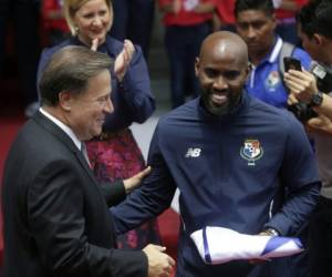 El jugador del equipo nacional de fútbol de Panamá, Felipe Baloy (R), recibe del presidente panameño Juan Carlos Varela la bandera nacional panameña, antes de su participación en la Copa Mundial de la FIFA, durante una ceremonia en el Palacio presidencial Las Garzas en la ciudad de Panamá.