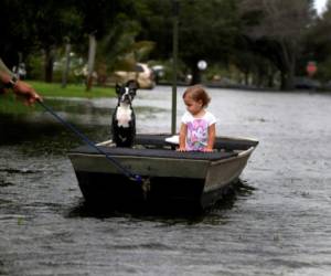 Lemay Acosta tira de un bote con su hija, Layla, de dos años, y su perro, Buster, dando un paseo en su barrio inundado en Plantation, Florida, el lunes 9 de noviembre de 2020, al día siguiente de que la tormenta tropical Eta tocara tierra en los Cayos de Florida e inundara partes del sur de Florida.