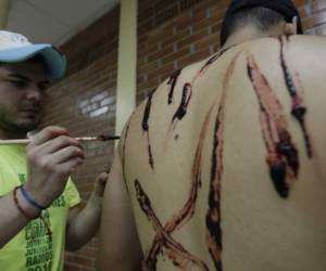 Malcon Ayax Zúñiga mostrando su arte mientras maquilla a uno de los personajes del Vía Crucis, foto: Fredy Rodríguez / EL HERALDO.