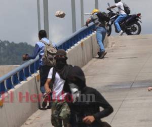 Un supuesto estudiante lanza una piedra desde el puente a desnivel del bulevar Suyapa de Tegucigalpa, capital de Honduras. Foto: Alex Pérez/EL HERALDO.