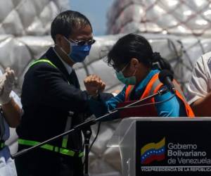 La vicepresidenta de Venezuela, Delcy Rodríguez y el embajador de la República Popular de China en Venezuela, Li Baorong, ambos con mascarillas como medida preventiva contra la propagación del coronavirus, COVID-19, se golpean los codos durante la llegada de un envío de 55 toneladas de ayuda humanitaria y equipo médico. Foto: Agencia AFP.