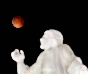 The moon is pictured over the El Salvador del Mundo Monument in San Salvador, El Salvador on April 15, 2014 as a lunar eclipse begins across the Americas. The entire event was to be visible from North and South America, but sky watchers in northern and and eastern Europe, eastern Africa, the Middle East and Central Asia were out of luck, according to US space agency NASA. AFP PHOTO/ Jose CABEZAS