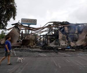 Un hombre pasa un banco que fue incendiado durante las protestas por la muerte de George Floyd en Mesa, California, 31 de mayo de 2020.