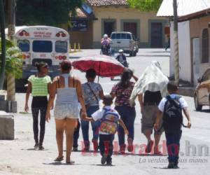 Los padres de familia optan por cubrir a sus hijos con sombrillas.