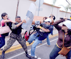 A Honduran soldier (C) --member of the presidential guard-- protects himself from being hit, during clashes with demonstrators protesting against the murder of journalists, in Tegucigalpa on December 13, 2011. In the past two years, and under the government of Porfirio Lobo, 17 journalists have been killed in Honduras. AFP PHOTO/Orlando SIERRA