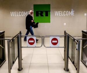 Esta foto de archivo tomada el 8 de junio de 2018 muestra a un hombre mientras pasa frente a un puesto de control de la compañía de televisión Russia Today (RT) en Moscú.