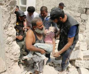 Varios hombres sirios cargan a una niña que quedó bajo los escombros de su vivienda tras bombardeo. Foto AFP.