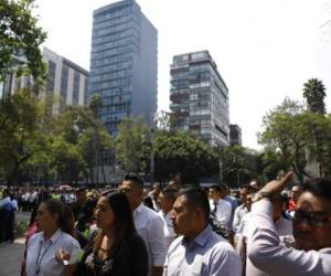 Trabajadores evacuados de un edificio federal después de un sismo aguardan en la acera de la avenida Paseo de la Reforma, en la Ciudad de México. (Foto: AP)