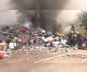 Bomberos intentando apagar el fuego en el negocio de chatarra.