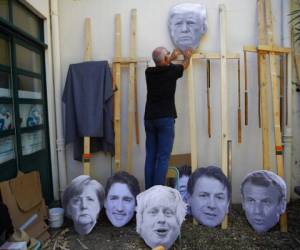 Un hombre fija una imagen del presidente de Estados Unidos, Donald Trump, en un palo de madera mientras se prepara para una manifestación contra el G7 en un campamento cerca de Hendaya, Francia. Foto. Agencia AP.