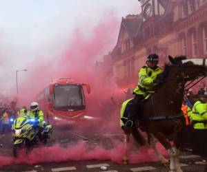 La policía mantiene el control mientras los jugadores del Liverpool llegan en autobús a través del humo y las bebidas antes del partido de cuartos de final de la Liga de Campeones de la UEFA entre Liverpool y Manchester City. Foto :AFP