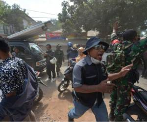 Un soldado indonesio y un funcionario intentan calmar a la población poco después de que una réplica azotara la zona de Tanjung, en Lombok. Foto AFP