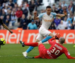 El mediocampista de Marsella Florian Thauvin, izquierda, se disputa el balón con el arquero de Nimes Paul Bernardoni en un partido de la liga francesa el sábado, 13 de abril del 2019. (AP Foto/Claude Paris)