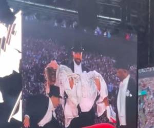 Travis Kelce cargando a Taylor Swift durante su concierto.