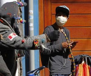 Una persona vestida como Kusillo, un arlequín andino tradicional, recuerda a la gente que debe usar máscaras faciales. Foto AFP