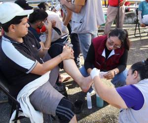 Un médico atiende a un migrante durante la más reciente caravana que salió del sur de México, en el municipio de Huixtla. Sus pies llagados por tanto caminar le obligaron a hacer una pausa en el camino.