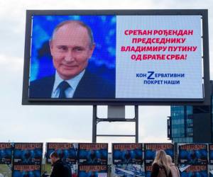 Los peatones pasan frente a una valla publicitaria firmada por el grupo de derecha prorruso ‘Nasi’ (Nuestro) que muestra al presidente ruso Vladimir Putin y una oración que dice: “¡Feliz cumpleaños al presidente Vladimir Putin de parte de los hermanos serbios!”, en Belgrado.