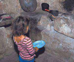 Una niña con hambre en el corredor seco se da cuenta que en la cocina de su deteriorada vivienda no hay alimentos.