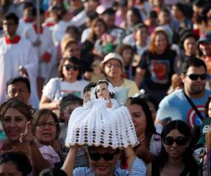 Una mujer sostiene a un Niño Jesús en procesión de los Santos Inocentes en Antiguo Cuscatlán. El Salvador.