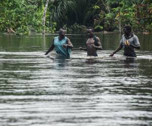 La gente camina a lo largo de la carretera este-oeste cortada por las inundaciones, lo que detuvo el movimiento de vehículos y actividades económicas, en la región del delta del Níger de Ahoada, estado de Rivers, sur de Nigeria.