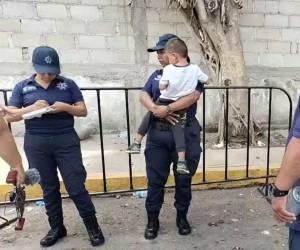 Una agente municipal sostenía al pequeño Caleb, mientras sus compañeros intentaban gestionar la búsqueda de sus padres o tutores.